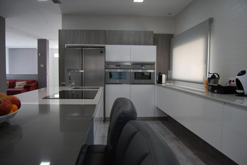 Cocina moderna en blanco brillo y madera, con isla y mesado · Kitchen in