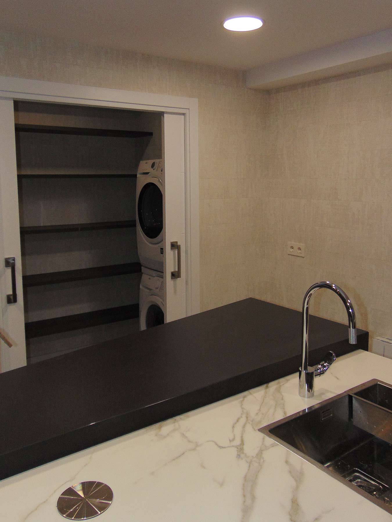 Cocina con zona de lavandería que incluye baldas, lavadora y secadora