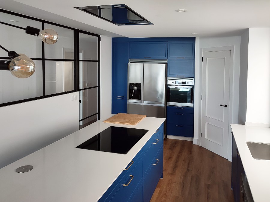 Cocina en laca mate color azul (carta NCS) con encimera encimera compacta de resina blanca y electrodomésticos en acero