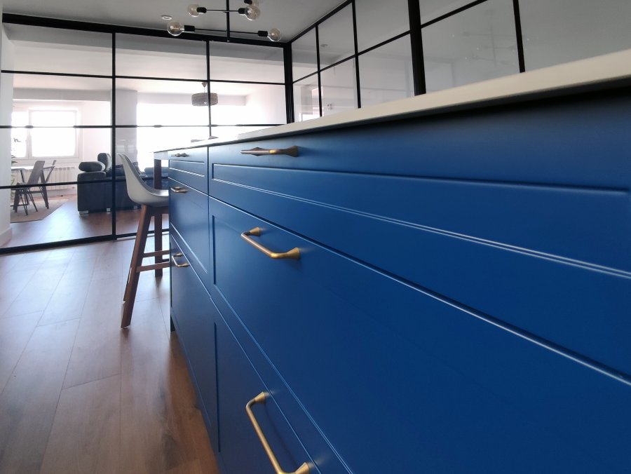 Detalle de puerta de cocina con marco en laca mate color azul y tirador dorado