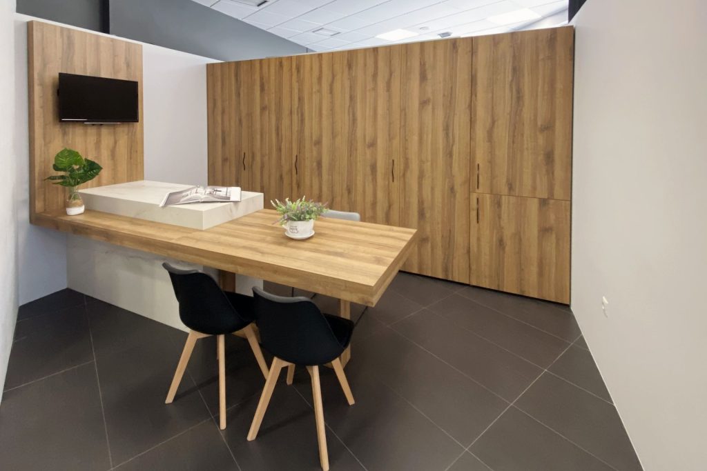 Vista lateral de cocina con puertas escamoteables cerradas en madera y península con mesa para comidas y sillas