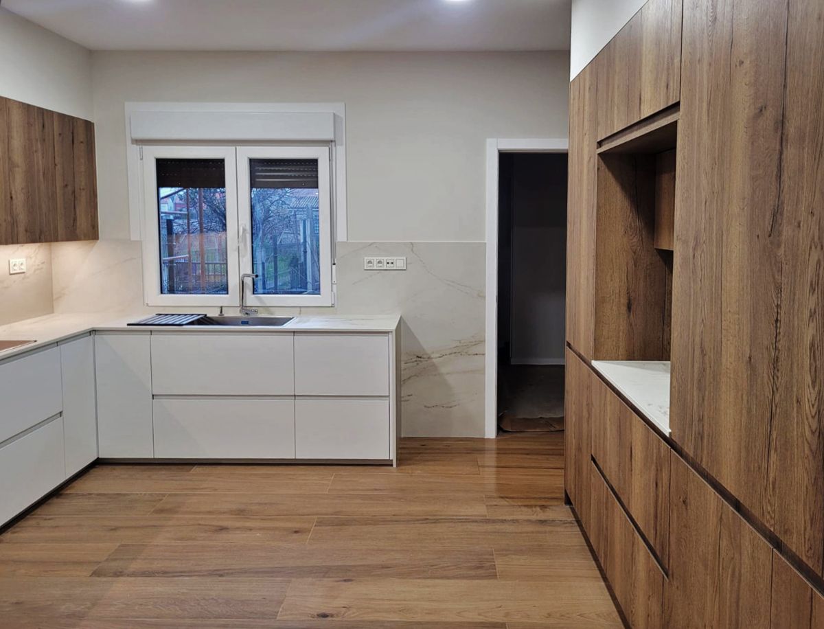 Vista frontal de cocina amplia con mobiliario en blanco y madera de dos frentes