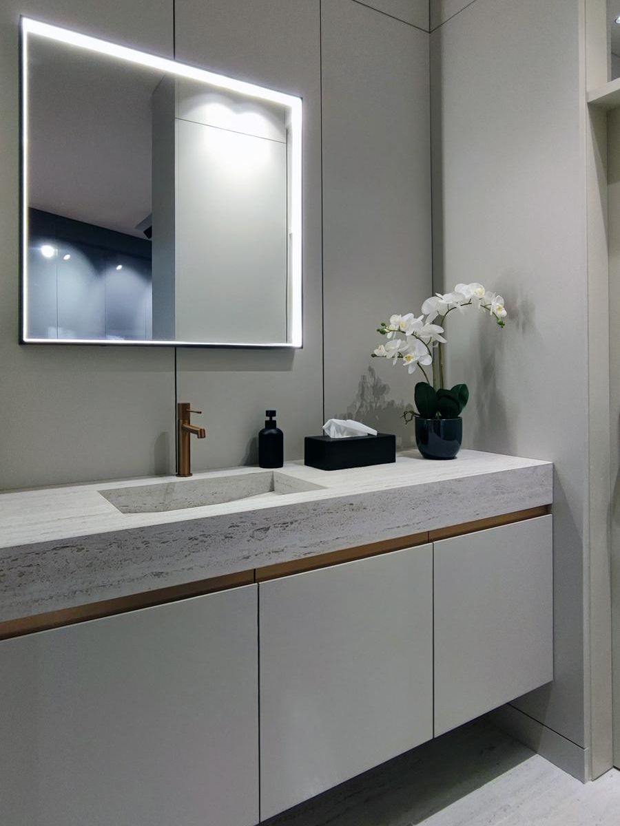 Baño moderno con mobiliario Fussion de Senssia, tiradores en cobre, grifo a juego y encimera con lavabo integrado en Dekton marmóreo. Piso revestido en Dekton marmóreo para un diseño uniforme y sofisticado.