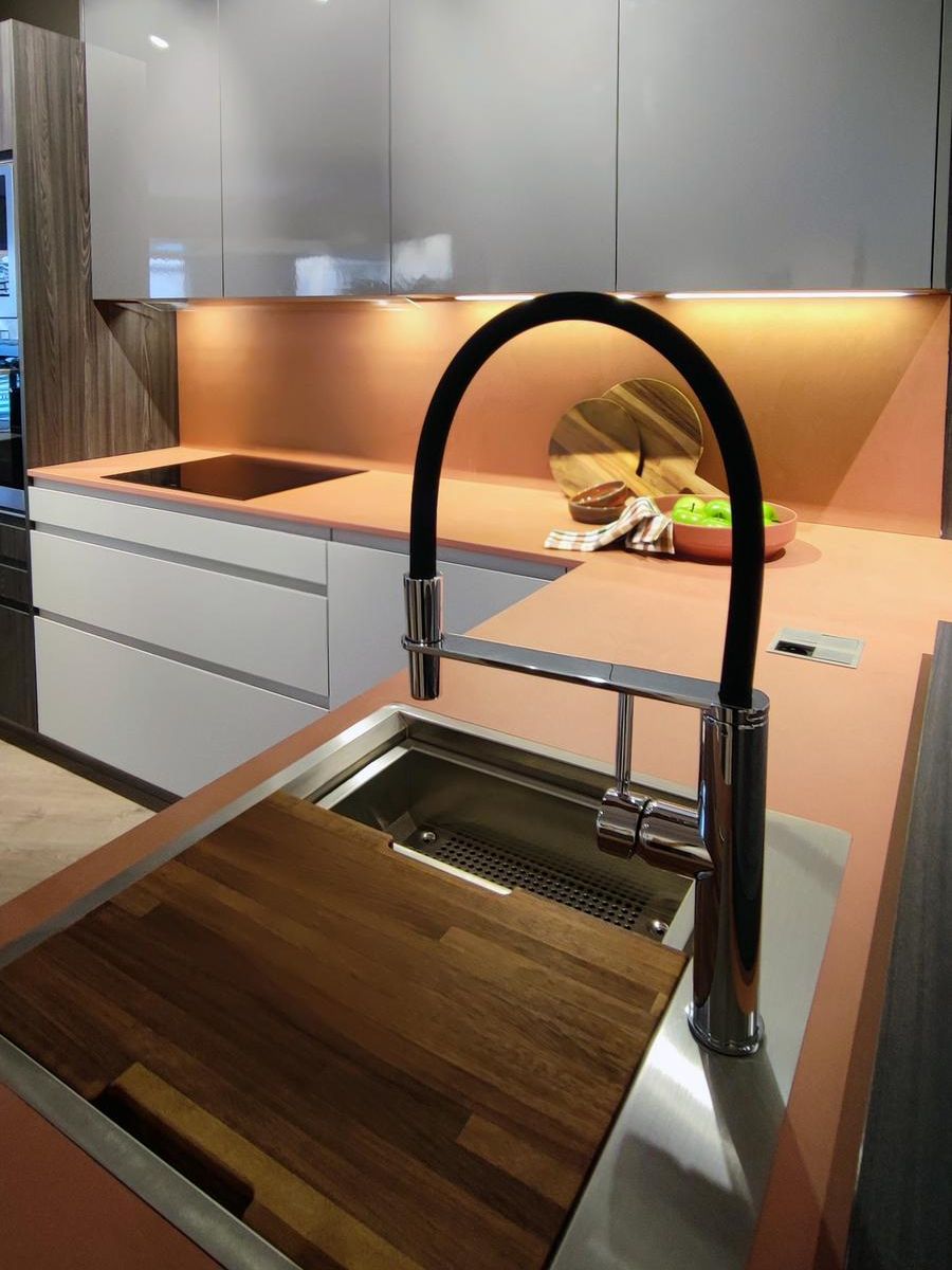 Detalle del fregadero en la cocina modelo Fussion de Senssia con bancada en Dekton Umbra color terracota, grifo moderno en acabado negro y tabla de corte integrada.