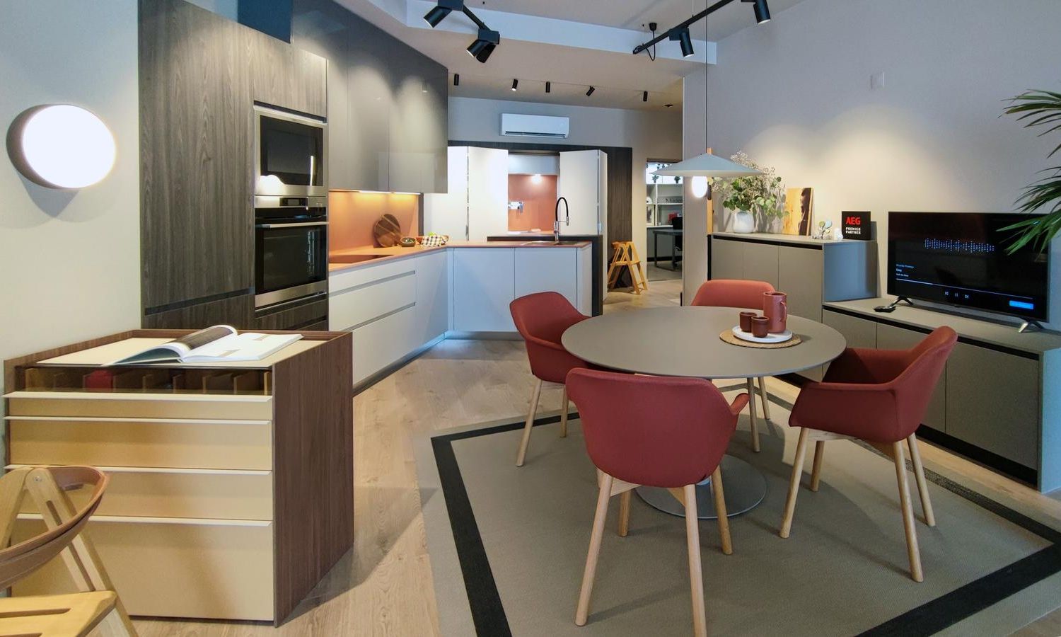 Interior de la tienda Kitchen in en Espinho (Portugal), mostrando una cocina modelo Fussion de Senssia con encimera en Dekton Umbra, electrodomésticos integrados y una elegante zona de comedor con mesa redonda y sillas en tonos cálidos.