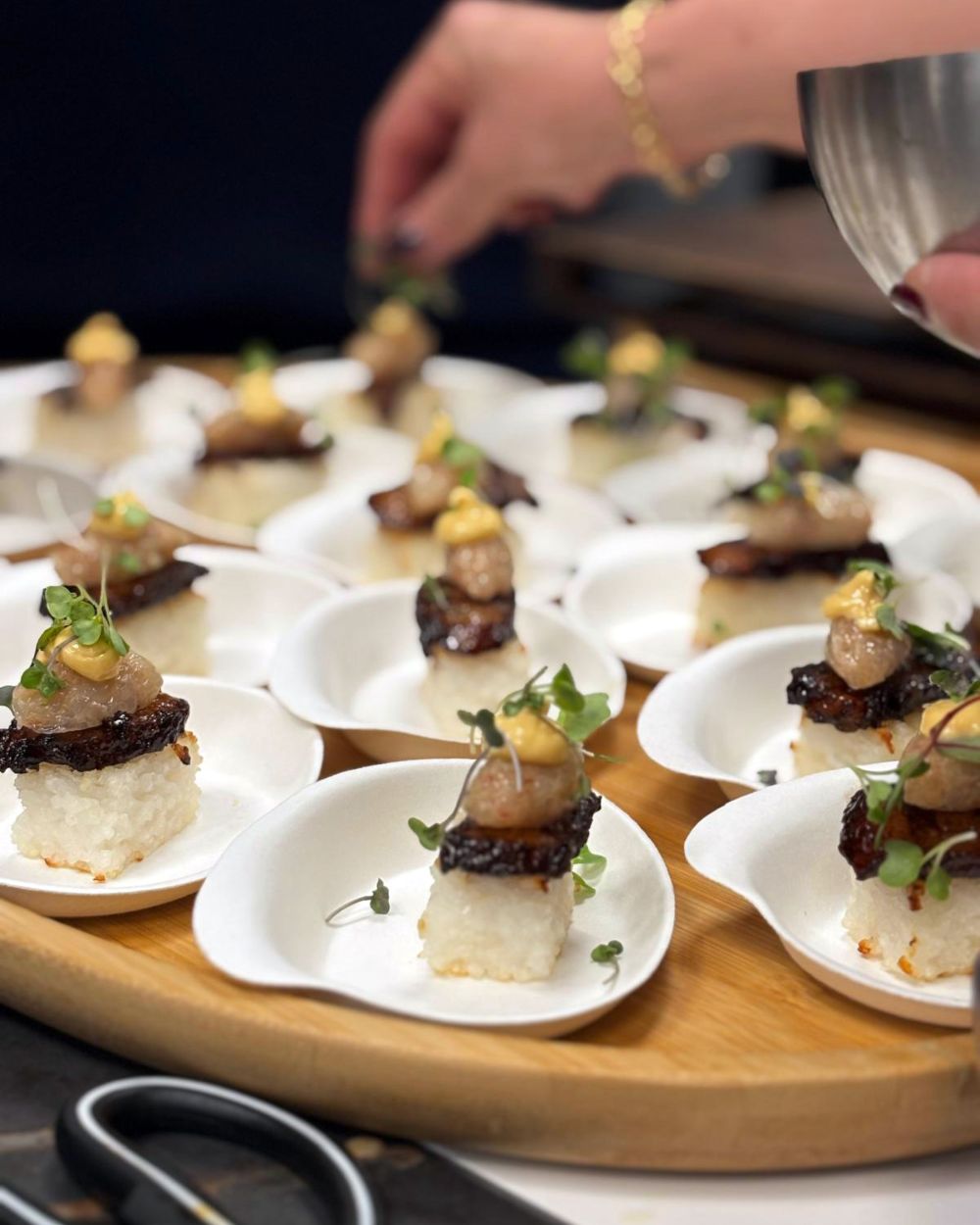 Bocados gourmet sobre bandeja de madera.