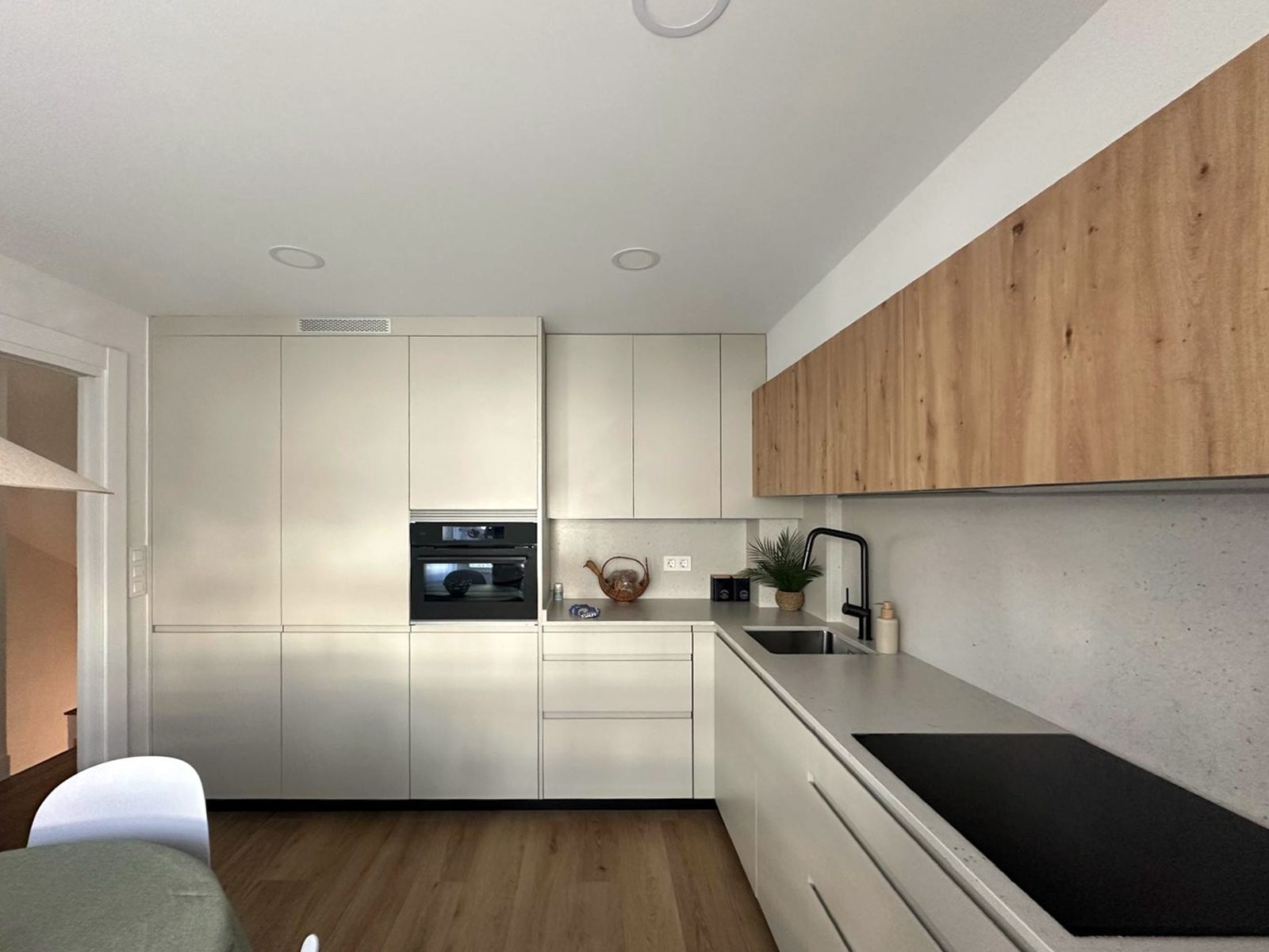 Cocina reformada en forma de L con muebles Fussion de Senssia en Beige Oliva y Roble Dorado y electrodomésticos AEG integrados