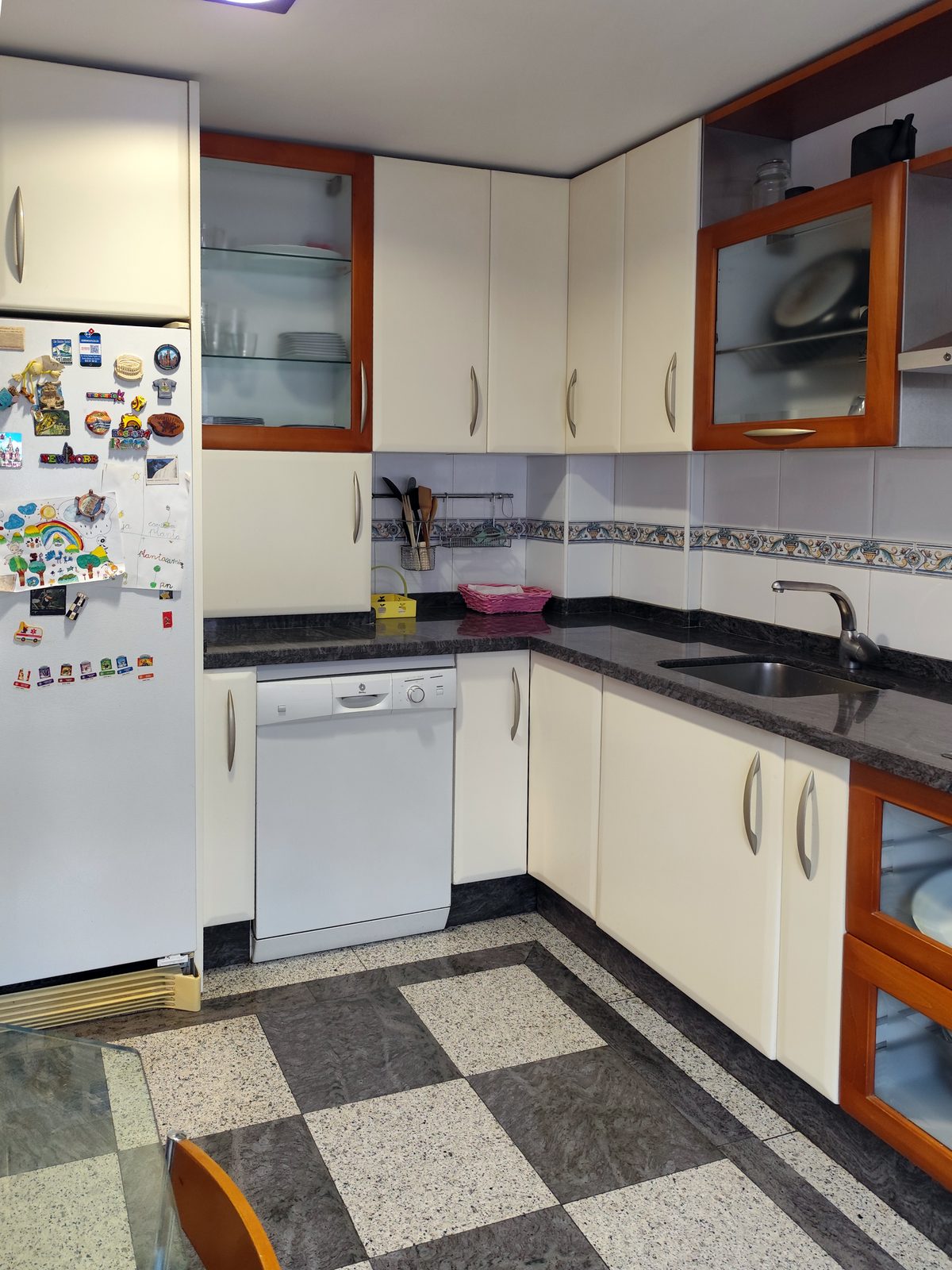 Antigua cocina tipo office antes de la reforma, con muebles blancos, encimera oscura y suelo de terrazo