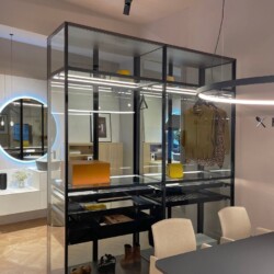 Armario vestidor realizado en aluminio lacado negro y cristal transparente Armario vestidor realizado en aluminio lacado negro y cristal transparente con composición de baño al fondo y logo Kitchen in a la derecha