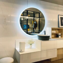 Composición moderna de baño con muebles bajos en color blanco y columna en color abeto natural Composición moderna de baño con muebles bajos en color blanco y columna en color abeto natural. Dispone de un gran espejo circular y el lavabo es sobreencimera