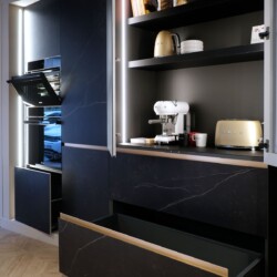 Composición de muebles columna con modelo FUSSION de Senssia en Kitchen in Salamanca Composición de mobiliario columna en aluminio y acabado cerámica con puertas abiertas y pequeños electrodomésticos en su interior