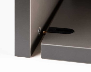Detalle del armado con tornillo desenroscado de un mueble Senssia en negro Detalle del tornillo y enganche pertenecientes a un armado de un módulo inferior de cocina en color negro
