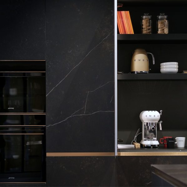 Composición de muebles columna en acabado cerámica con mueble abierto que contiene pequeños electrodomésticos de cocina y otros elementos.