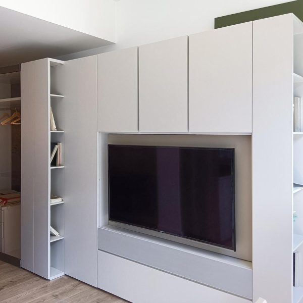 Vista lateral de armario con zona para televisor y televisor integrado y estanterías con libros