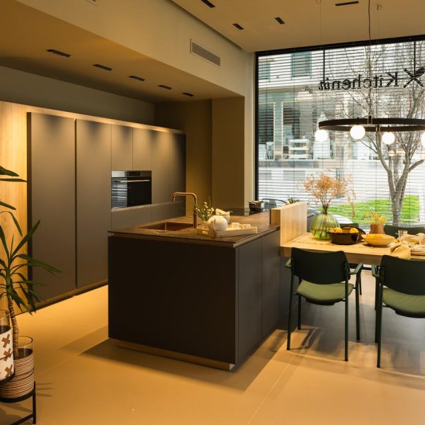 Cocina moderna con isla central en exposición tienda Kitchen in Santiago con armario en Verde Comodoro Fénix y detalles en Roble Testa.