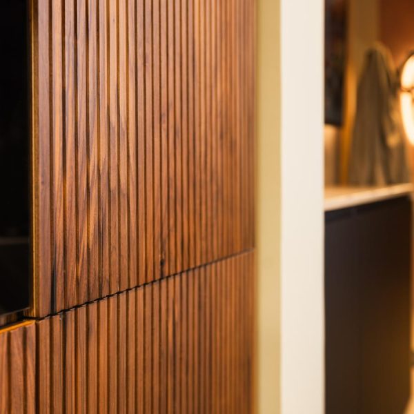 Detalle de las puertas modelo Coral en madera natural Nogal, con diseño vertical texturizado y acabado sofisticado, en exposición de cocinas Kitchen in Santiago.