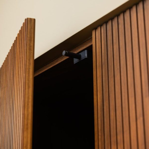 Detalle del sistema push electrónico en una puerta modelo Coral de madera natural Nogal, sin tirador, en la cocina de la exposición de Kitchen in Santiago.