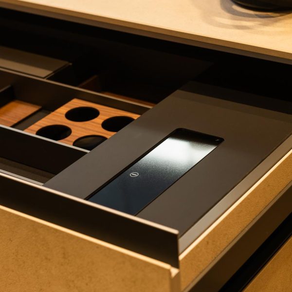Detalle del cajón bajo encimera de península modelo Fussion con frentes en cerámica Ananda y compartimentos de madera y cristal, en exposición Kitchen in Santiago