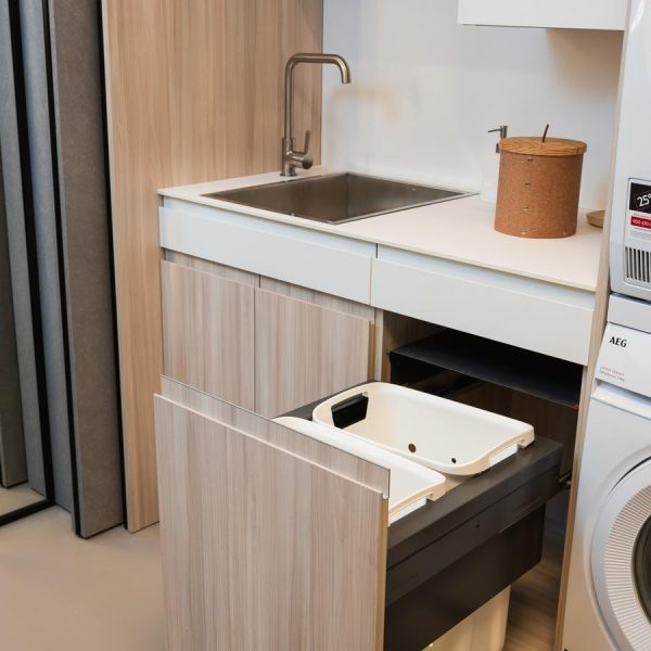 Lavandería moderna en exposición tienda Kitchen in Santiago con bajo fregadero, cajones extraíbles para reciclaje y electrodomésticos AEG.