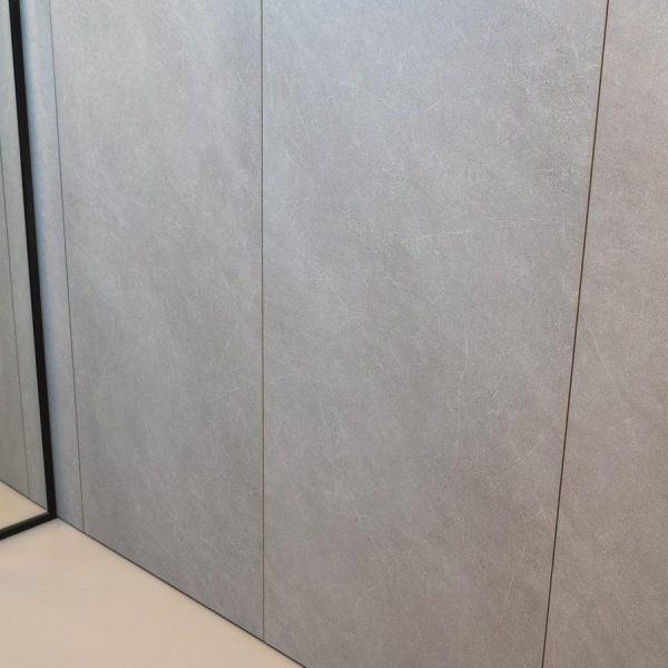 Detalle de puertas escamoteables en acabado Quartzite que ocultan una zona de lavandería funcional en exposición tienda Kitchen in Santiago.