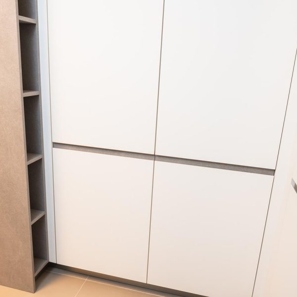 Armarios columna con puerta Fussion aglomerado en acabado blanco Fénix y tiradores integrados en la exposición renovada de Kitchen in Santiago.