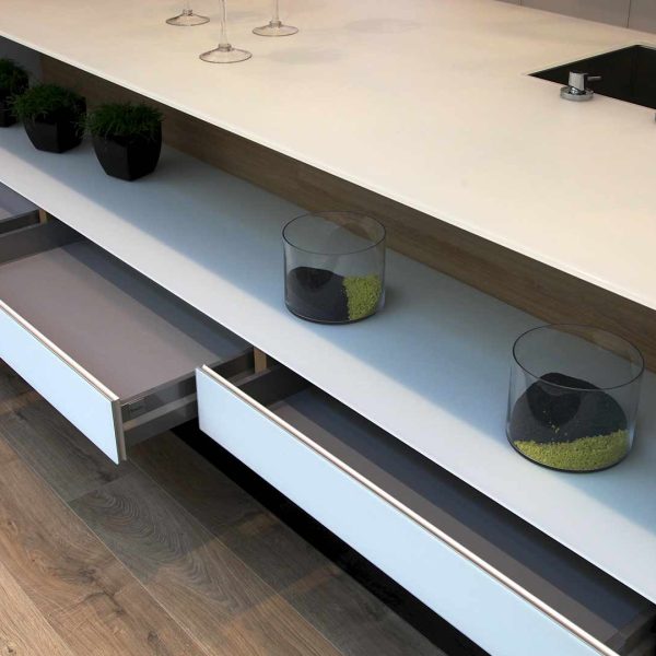 Cajones inferiores abiertos de una península de cocina con encimera en cristal templado en Kitchen in Vigo