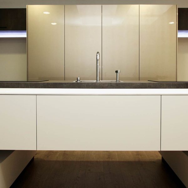 Isla de cocina moderna en color blanco con muebles columna color brillo al fondo, en Vigo