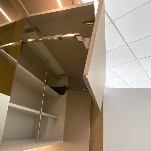 Detalle de armario blanco abierto con estantes en su interior e iluminación led arriba